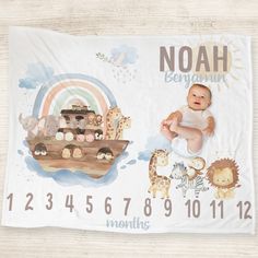 a baby laying on top of a wooden floor next to a noah sign with animals