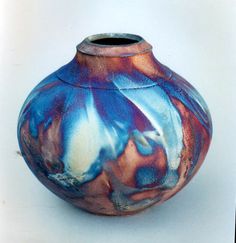 a blue and red vase sitting on top of a white table