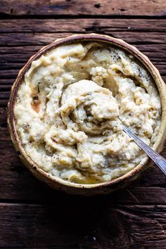 a bowl filled with mashed potatoes on top of a wooden table