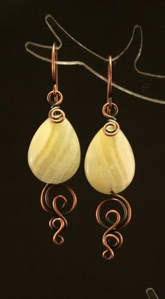 the earrings are made with wire and marbles in gold plated brass, set against a black background