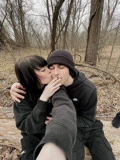 two people sitting on the ground kissing each other