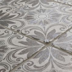 a close up view of a tile floor with silver and white designs on it's surface