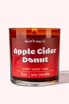 an apple cider donut candle sitting on top of a white table next to a pink background