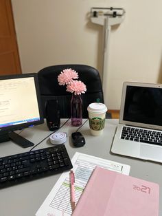 a laptop computer sitting on top of a desk next to a cup of coffee and a pink flower