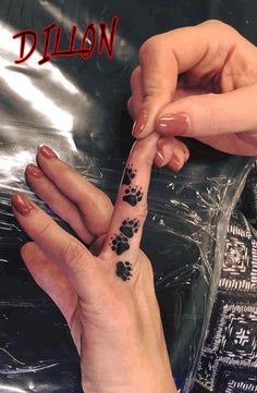 two hands holding each other with black ink on their fingers and paw prints on them