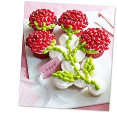 cupcakes decorated with raspberries and white frosting on a plate next to a pink napkin