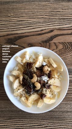 a white bowl filled with bananas and nuts on top of a wooden table next to a spoon