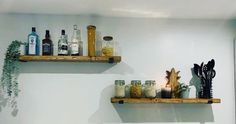 two wooden shelves filled with bottles and jars on top of a white wall next to a mirror