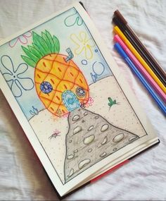 a coloring book with an image of a pineapple on it and colored pencils next to it