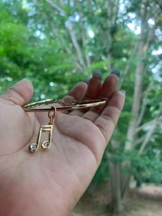 a person holding up a pair of scissors in their left hand with trees in the background