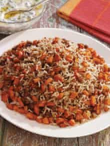 a white plate topped with rice and carrots on top of a wooden table next to a glass bowl