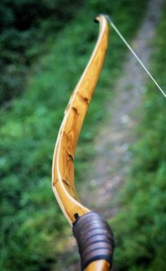 a bow and arrow on the back of a wooden bicycle handlebars in front of some green grass