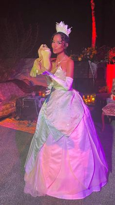 a woman dressed in a princess costume holding a stuffed animal and wearing a tiara