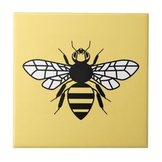 a yellow tile with a black and white bee on it's back side, against a light yellow background