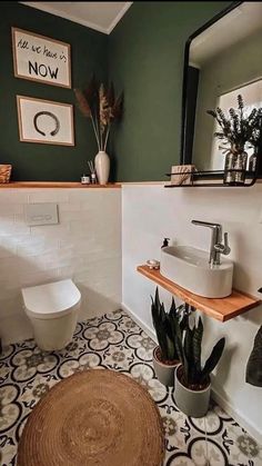 a bathroom with green walls and black and white tile flooring, potted plants on the counter