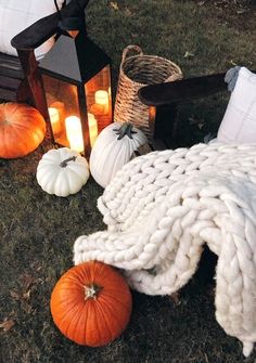 pumpkins and blankets on the ground next to lanterns