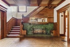 an empty living room with wood paneling and green tile on the fireplace mantel