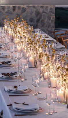 a long table is set up with candles and place settings for dinner guests to enjoy