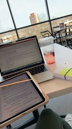 two laptops sitting on top of a table next to a cup of coffee and a book