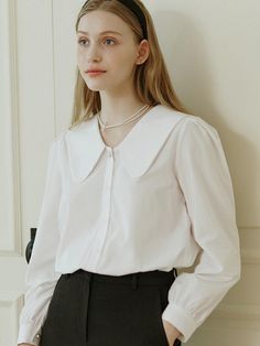 This is NONLOCAL’s blouse exudes a clean look. It's made from a soft-touch blend of rayon and cotton, offering a luxurious feel with just the right amount of flow. The subtle shirring on the shoulders and cuffs, along with the classic flat collar line, stand out. The pearl button accents on the sleeves add a feminine touch.- Ideal for daily wear- Can be paired with different bottoms to create various looks- Features back pleat detailing and brand logo symbol embroidery on the side for added flair Timeless Collared Tops For Office, Timeless White Tops For Workwear, Timeless White Tops For Work, Timeless White Workwear Tops, Timeless White Blouse For Work, Timeless White Tops For Daywear, Timeless White Office Tops, White Timeless Collared Top, Timeless White Collared Top