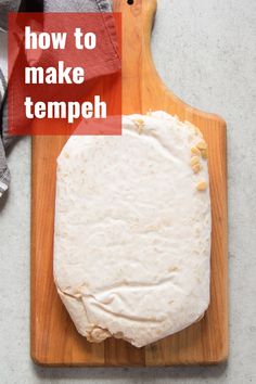 a wooden cutting board with a piece of bread on it and the words a guide to tempeh