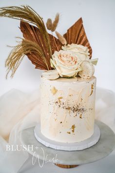 a white cake with flowers and feathers on top