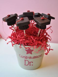 some cupcakes are sitting in a bucket with red streamers on them and graduation decorations