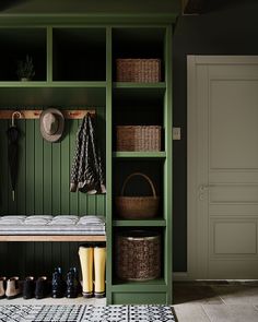 a green coat rack with shoes and umbrellas on it next to a rug in front of a door