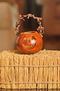 a pumpkin shaped vase sitting on top of a straw basket with an evil face carved into it