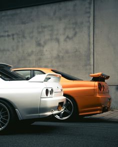 two cars parked next to each other in front of a building with concrete wall behind them