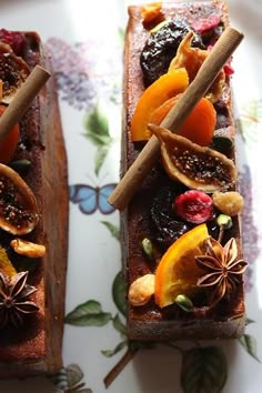 two slices of bread topped with fruit and cinnamon sticks on top of a floral plate