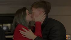 a man and woman kissing each other while standing next to each other