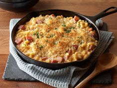 a skillet filled with macaroni and cheese on top of a wooden table