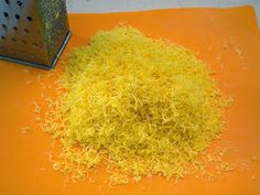 a pile of shredded yellow food next to a grater