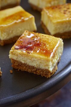 several pieces of dessert sitting on top of a black plate with brown sugar and caramel toppings