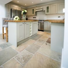 a large kitchen with white cabinets and wooden counter tops, along with an island in the middle