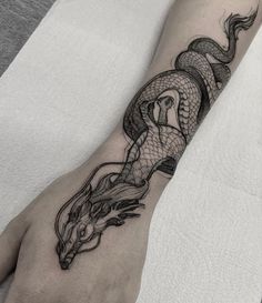 a woman's arm with a dragon tattoo on the left side of her hand