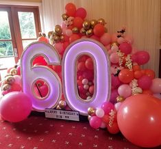 the number sixty is surrounded by balloons and streamers in pink, orange, and gold