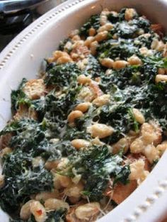 a white dish filled with pasta and spinach