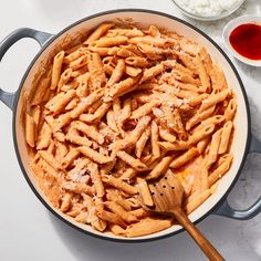 a pan filled with pasta and sauce on top of a white counter next to other ingredients