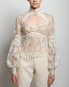 A sheer lace blouse with a high neck and hand placed embroidery at collar and cuff closures. The Eliza blouse features a fitted empire cut along with front décolletage and raglan romantic billow sleeves. French lace lined with nude color mesh Delicate satin button closure for collar, cuffs and front Dry clean only Each piece is made to order and handcrafted in our atelier. Slight variations may occur as each piece is unique. Romantic Blouses, High Neck Blouse, Unique Blouse, Lace Outfit, French Lace, Dress Cuts, Sheer Blouse, Collar And Cuff, Lace Blouse