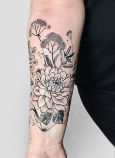 a woman's arm with black and white flowers on the left side of her arm