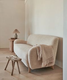 a couch with a blanket on it next to a small table and lamp in a room