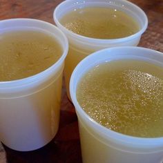 three plastic cups filled with liquid on top of a wooden table