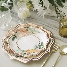 there is a plate with flowers on it and gold spoons next to the plates