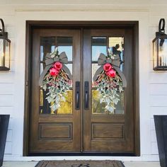 the front door is decorated with wreaths and lanterns