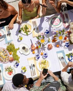 a group of people sitting around a table with food and drinks on top of it