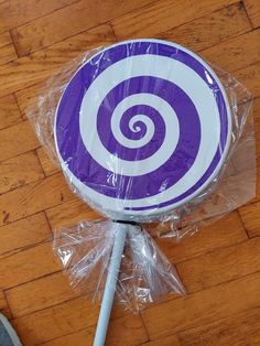 a purple and white lollipop sitting on top of a wooden floor