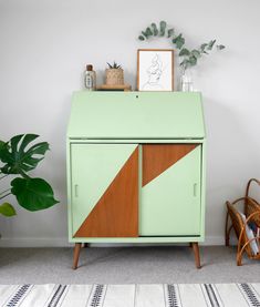 a green cabinet sitting next to a potted plant