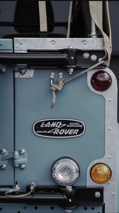 the front end of an old jeep with its lights on and rope hanging from it